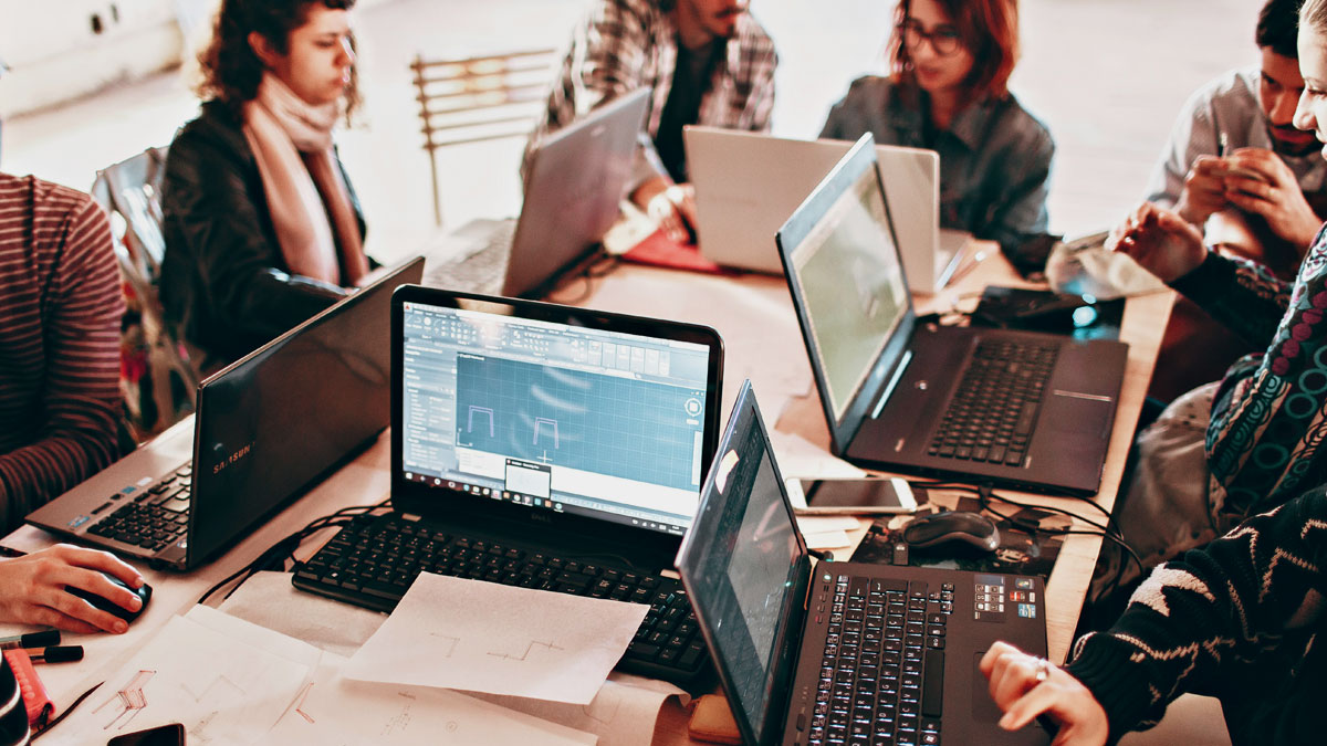 転職や職場の人間関係の悩みを抱え、PCを囲んで真剣に話し合う複数の男女。仕事の悩みに強い電話占いを探すビジネスパーソンのイメージ。